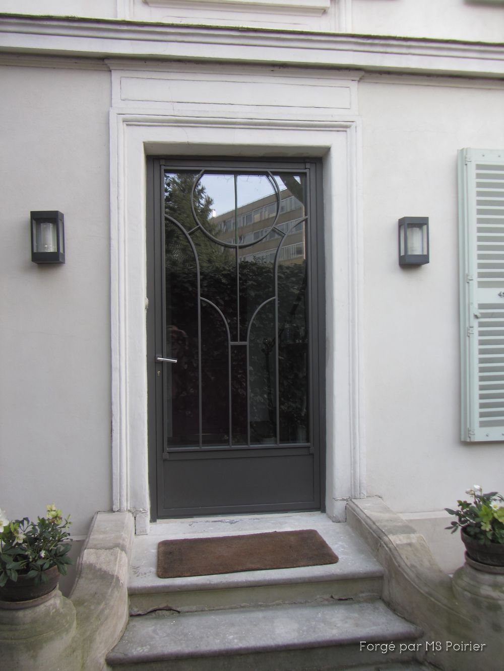 Porte d'entrée en fer forgé sur perron en pierre