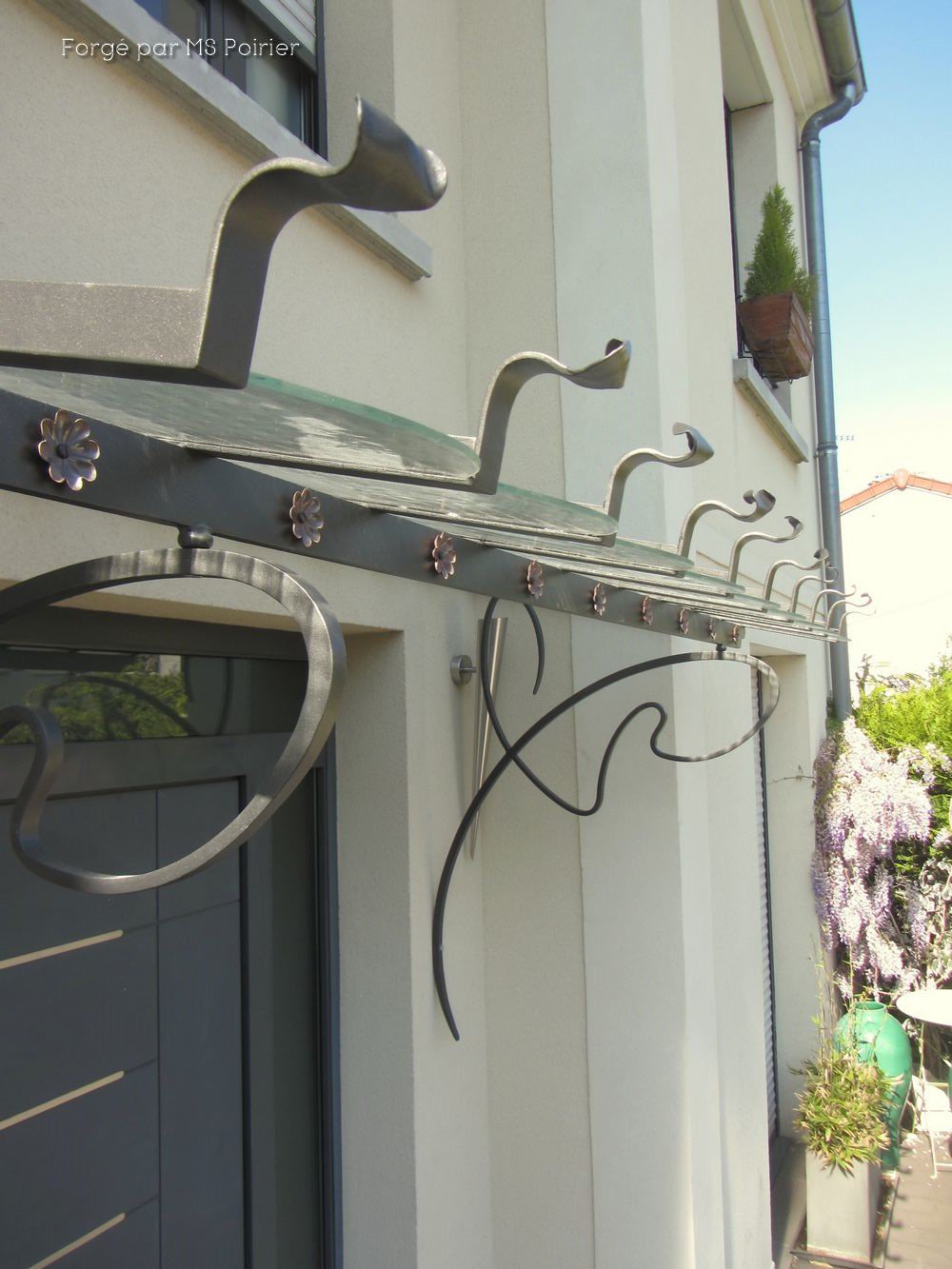 détail du bandeau de la marquise avec rosace laiton et rouleau en fer forgé